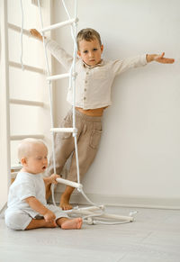 Children are exercising on toddler indoor gym playset. kid climbing the ladder in playroom. siblings