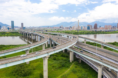 Bridge over river amidst buildings in city against sky