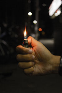 Close-up of hand holding illuminated candles