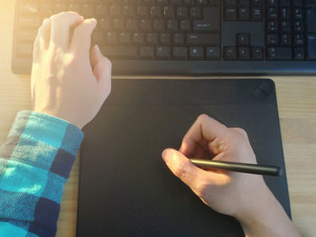 Cropped hands of man using graphic tablet on table