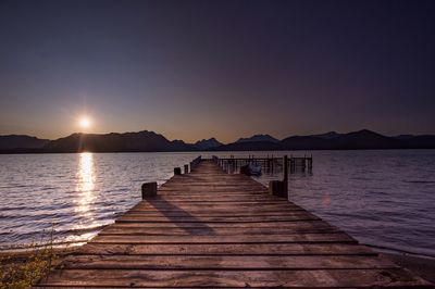 Pier over lake against sky during sunset