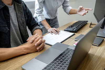 Midsection of man using laptop on table