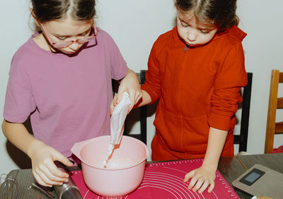 Two beautiful caucasian girls are baking cookies.