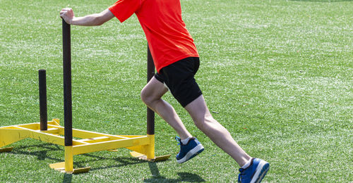 Low section of man exercising with sled on turf ground