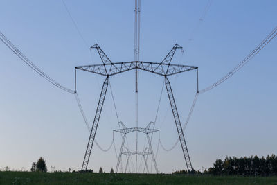 Huge power line towers on field at summer evening.