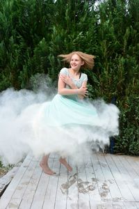 Happy girl spinning on boardwalk against plants