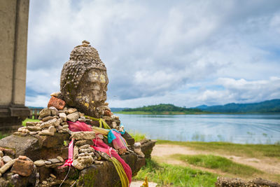 Statue sitting on rock against sky