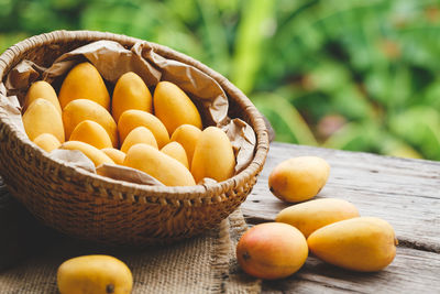 High angle view of mangoes in basket with burlap on wooden table