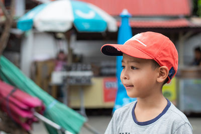 Cute boy wearing cap looking away while standing on road