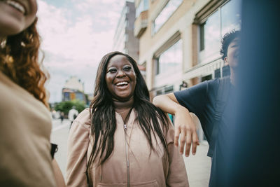 Happy long haired teenage girl enjoying with friends in city