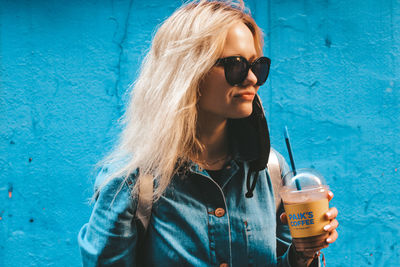 Young woman drinking water from sunglasses