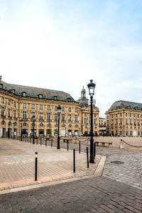 Lamp posts on sidewalk against place de la bourse in city