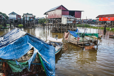 Boats moored on river by houses against sky