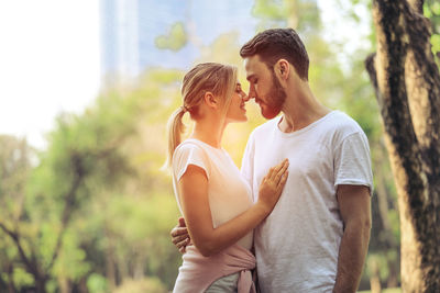 Side view of couple standing against trees