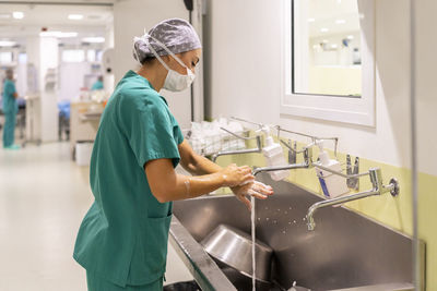 Nurse wearing mask washing hands in hospital