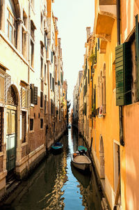 Boats in canal amidst buildings against sky in city