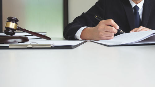 Midsection of man holding paper at table