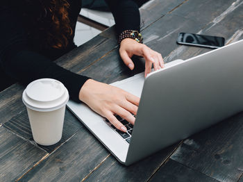 Midsection of woman using laptop at table in office