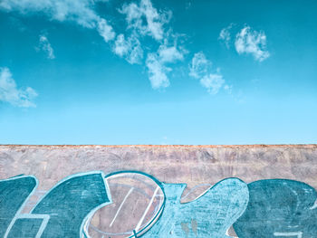 Low angle view of graffiti on wall against blue sky