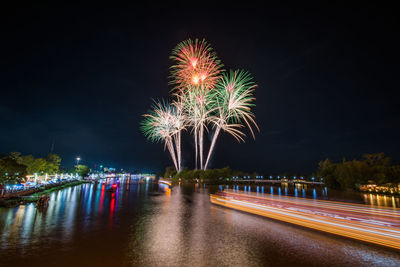 Firework display over river against sky at night