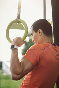 Man holding rings and doing chin-ups at park