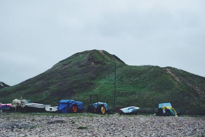 Tractors and boats by mountain against sky