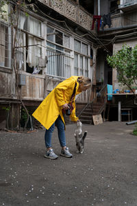 Young photographer girl playing with cat on the street in old city