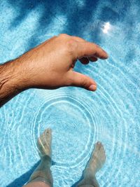 Optical illusion of man holding ripples in swimming pool