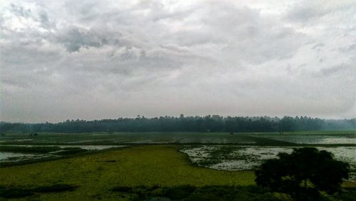 Scenic view of field against cloudy sky