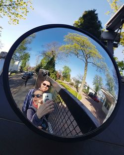 Happy young couple on side-view mirror against sky