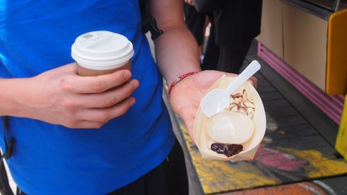 Midsection of woman holding coffee cup and food