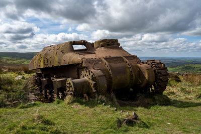 Abandoned car on field against sky