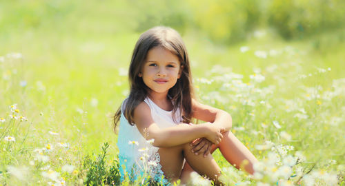 Portrait of young woman with arms raised standing against plants