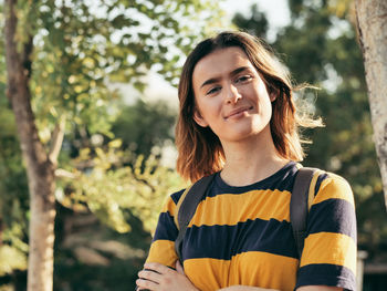 Portrait of smiling young woman against trees