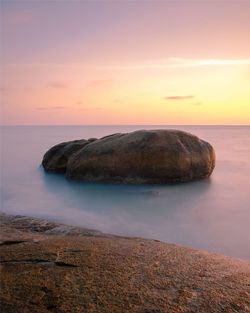 Scenic view of rocks in sea against sky during sunset