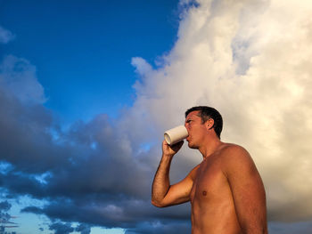 Generation x young man drinking coffee on the beach.