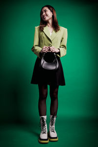 Portrait of young woman standing against blue background