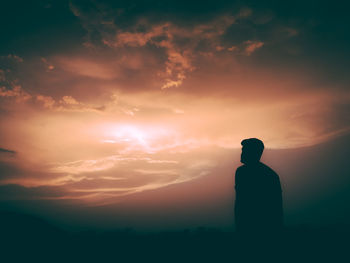 Silhouette man standing against cloudy sky during sunset