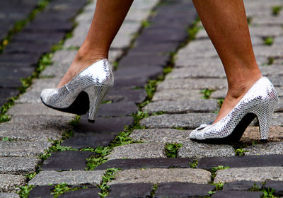 Low section of woman in high heels walking on footpath