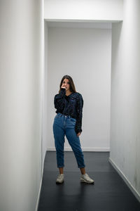 Portrait of woman standing in corridor against wall 