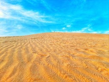 Sand dune in desert against blue sky