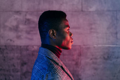 Portrait of young man looking away against wall