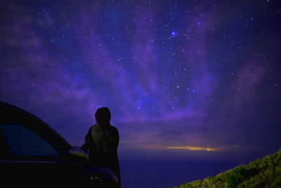 Girl standing against sky at night