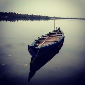 Boat moored in lake against sky