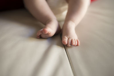 Low section of baby with bare feet on bed