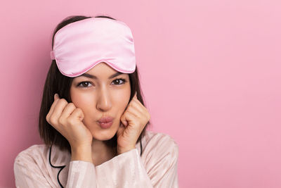 Portrait of young woman against pink background