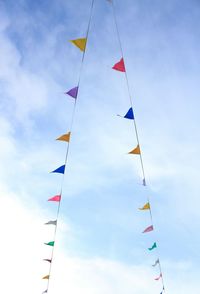 Low angle view of colorful flags against cloudy sky