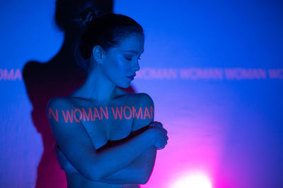 Woman standing against pink wall