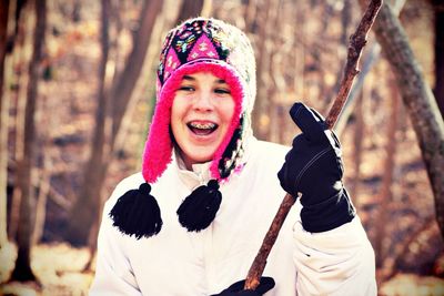 Smiling woman with warm cloth holding stick