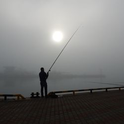 Man fishing in calm sea at night